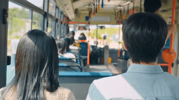 Imagen de dos pasajeros en un autobús urbano mostrando la vista desde atrás hacia el interior del vehículo y otros pasajeros