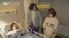 Dos mujeres en un hospital junto a una paciente en cama una de ellas sostiene un dispositivo médico