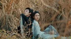 Hombre y mujer con ropa tradicional china sentados en medio de la hierba alta