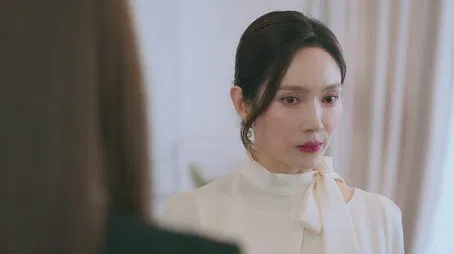 Primer plano de una mujer con una camisa de cuello blanco, episodio 1.