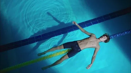 Nadador flotando de espaldas en la piscina durante el episodio 02.