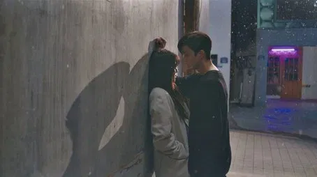 Pareja romántica abrazándose en un callejón poco iluminado.