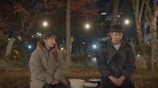 Dos personas sentadas al aire libre por la noche, conversando. Episodio 10.