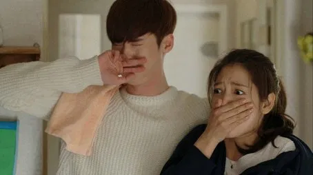 Un hombre y una mujer reaccionan con sorpresa y tristeza, tapándose la boca con las manos.