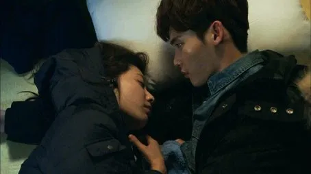 Primer plano de una pareja joven acostados uno junto al otro, mirándose amorosamente.