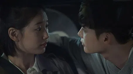 Primer plano de un hombre y una mujer mirándose intensamente en un automóvil.