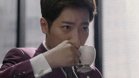 Hombre con traje morado bebiendo té